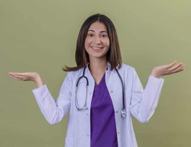 young woman doctor wearing white coat and with stethoscope clueless and confused expression with arms and hands raised over isolated green background young woman doctor wearing white coat and with stethoscope clueless and confused expression with arms and hands raised over isolated green background